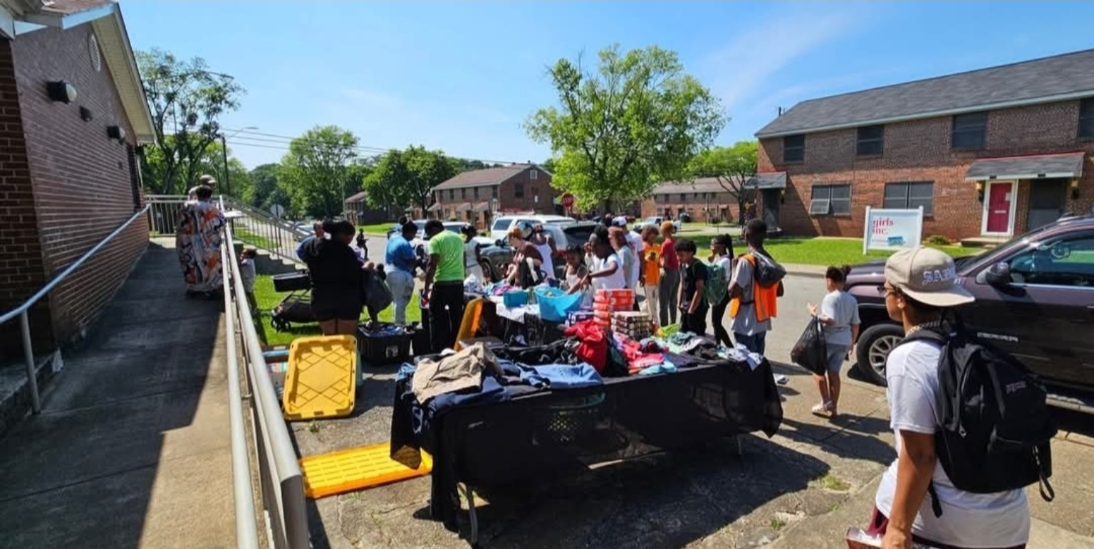 Families choosing items from tables at a neighborhood community pop-up