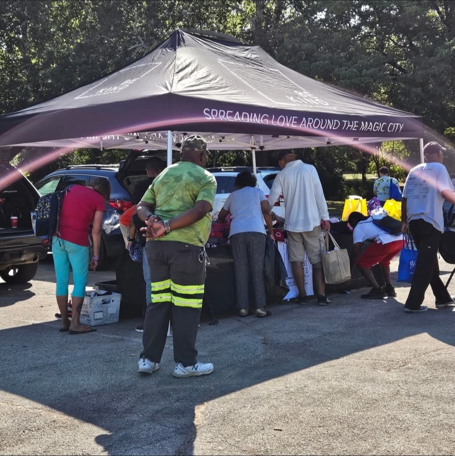 Community members selecting essentials beneath the Be Kind Birmingham tent