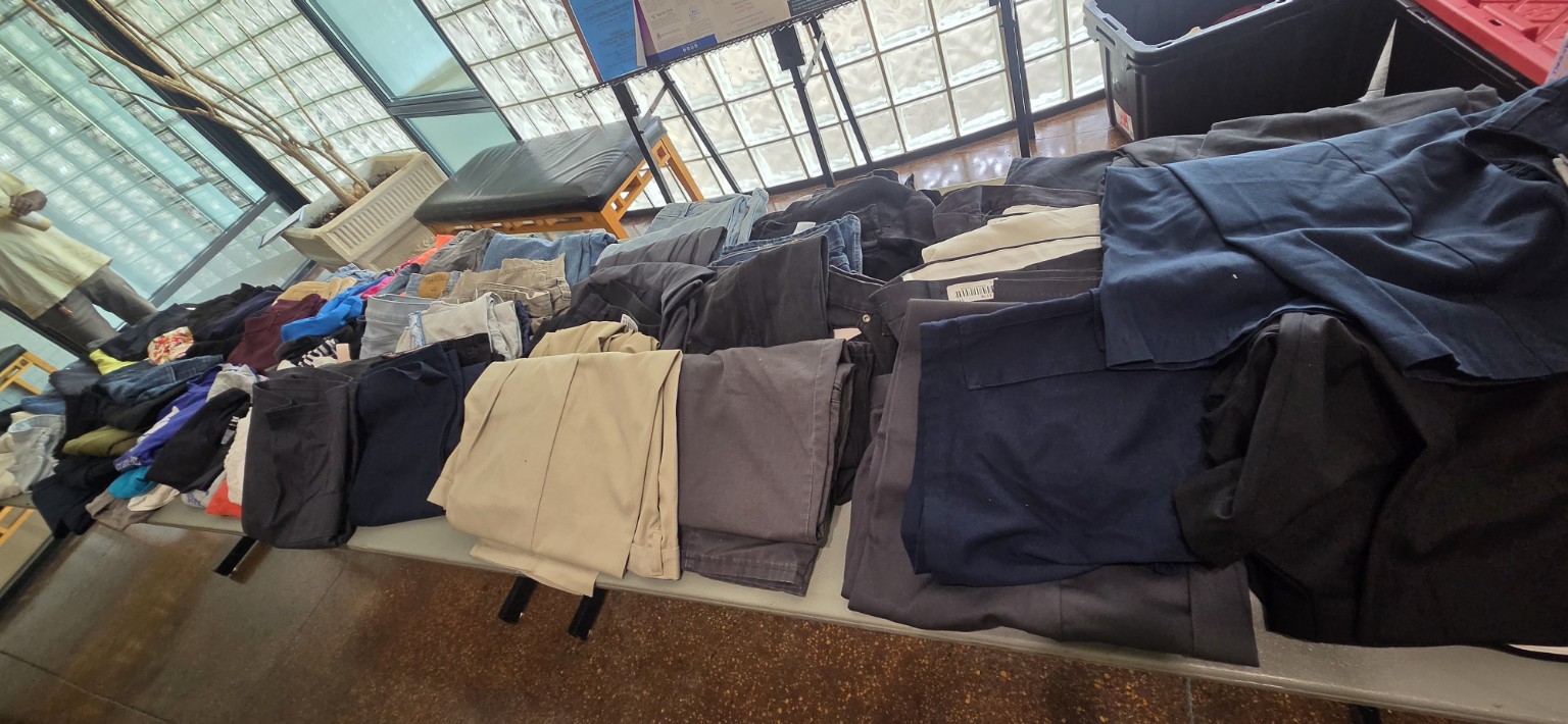 Work pants and practical clothing arranged by type at a Be Kind Birmingham library pop-up